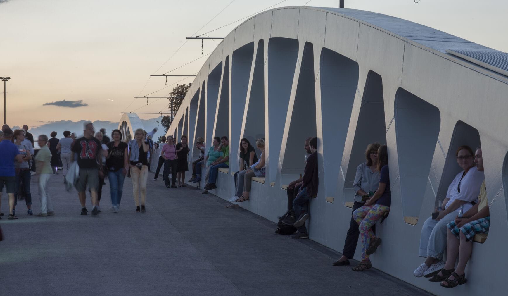 People sitting and walking on a bridge